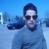 Pixelated blue-toned image of a figure with dark hair and sunglasses against a gradient blue background.