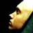 Pixelated static image of a person's face in profile view with yellowish skin tones and dark hair against black background, partially cropped on right side.