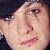 Pixelated close-up of a person's face showing eyes, nose, and mouth with pink lips against a dark background.