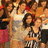 A pixelated static image shows a group of people in warm-toned clothing with visible red and brown hues, some holding objects.