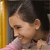 Pixelated close-up of a person with dark hair tied back, wearing a light pink garment, against a dark background with a vertical yellow stripe on the left.