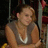 A pixelated image of a woman in a brown sleeveless top and white necklace, with red text on blue and gray backgrounds.