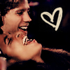 A pixelated image shows two people in close embrace, one holding the other's face, with a white heart symbol on a dark background.