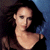 Pixelated static image of a person with dark hair and light skin, wearing a dark top against a blue and dark background.