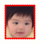 A child with dark hair and blue eyes appears in two , first facing forward then turning slightly right, framed by a red dotted border