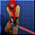 Pixelated figure with red hooded cloak, brown skin, and blue pants holding a red lightsaber against a blue background.