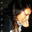 Pixelated image of a person with light skin and brown hair, wearing a white shirt, against a dark background with scattered light spots.