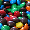 A dense cluster of colorful, glossy, oval-shaped candies with smooth surfaces and visible highlights.