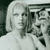 Pixelated grayscale image of a person with light hair and a white top, partially obscured by dark and light gray shapes on the right side.