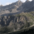 Pixelated static image showing a landscape with mountains, sky, and grassy terrain in muted tones.