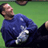 Pixelated static image of a person in blue sports attire lying on green grass with visible white and silver accents.