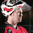 Pixelated image of a person in red sports attire with white and black helmet, surrounded by red text on black background.