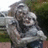 Pixelated static image of two figures in close embrace, one with light hair and the other dark hair, set against a blurred outdoor background.