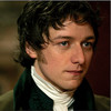 Static close-up of a person with curly dark hair wearing historical clothing against a blurred background.