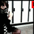 A person in a black outfit with white accents stands behind vertical bars, holding an object near their face; red text overlays appear on the image.