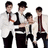 Four individuals in white jackets and dark pants pose together with one person leaning forward, accompanied by text reading 'panic at the disco' and 'ROCKS!' on a white background.