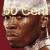 Static pixelated image of a person wearing a white cap with yellow text, set against a solid red background.