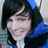 Pixelated close-up of a person with dark hair and blue clothing, smiling slightly against a blurred background.