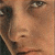 A pixelated close-up of a person's face showing eyes, nose, and mouth with visible skin tones and dark hair on the left side.