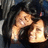 Two pixelated figures in close physical contact, one with light skin and dark hair embracing another figure from behind against a dark background.