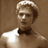Static pixelated image of a person in formal attire with light-colored hair and a bow tie against a brown background.