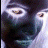 Pixelated close-up of a person's face with dark hair, light skin tones, and visible eyes against a pale background.