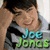 Pixelated image of a person with dark hair and a gray shirt, next to a group of five people holding guitars, with 'Joe Jonas' text in blue and green and 'JOE JONAS!!' in pink on a black background.