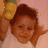 Pixelated close-up of a person with brown hair wearing a white top, holding an orange object near their head against a pink background.