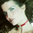 Pixelated static icon of a person's face with light skin, dark hair, and red lips against a dark background.
