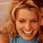 Static 48x48 pixel icon showing a close-up of a person with long wavy light brown hair wearing a blue top, smiling with eyes closed against a beige background.