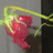 A red heart-shaped object with green vine-like elements, partially displaying text reading "Jesus Loves Me" in a pixelated style.