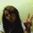 A pixelated image of a person with long dark hair wearing a white shirt, making a peace sign with their right hand against a light green background.