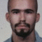 Four static portrait images of a man with a goatee, displayed in a with varying background colors and clothing