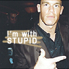A pixelated image of a person in a dark jacket and black shirt pointing with their right hand, with overlaid text reading "I'm with STUPID" on a dark background.