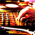A static pixelated image shows a fiery explosion with orange, red, and yellow hues, featuring a central bright white burst and scattered dark fragments against a black background.