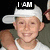 Pixelated image of a person wearing a white cap and sleeveless shirt with text overlays "I AM" and "Optimus Prime" on a dark background.