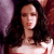 A static pixelated image of a person with long dark hair wearing a light-colored strapless top against a blurred background with purple and red tones.