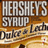 A pixelated image split into two sections: left shows 'HERSHEY'S SYRUP' text over a brown background, right displays orange with black text reading 'LOOK! it says latte!' in all caps.