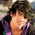 A person with dark tousled hair wears a purple hoodie over a black shirt, shown in three sequential poses against a blurred background.