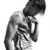 Black-and-white image of a person with short hair holding their hand to their face, wearing a sleeveless shirt with visible text on it.