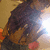 A pixelated image of a person in dark clothing holding an object, with bright light effects and red accents on the background.
