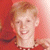 Pixelated image of a person with light hair in red clothing against a pinkish-red background, next to blue text on gray.