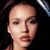 Pixelated close-up of a person's face with dark hair against black background, showing eyes nose mouth and neck in warm tones.