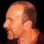 Pixelated close-up of a person's head and shoulder in profile view against dark background, with visible pixelation artifacts and warm color tones.