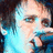 Pixelated close-up of a person with light skin tone wearing blue clothing, dark hair visible on left side.