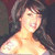 Pixelated image of a person with dark hair and light skin, wearing a light-colored top, against a dark background.