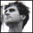 Pixelated grayscale image of a person's head and shoulders in profile view with dark hair, visible facial features including eye, nose, mouth, and ear, against a white background.