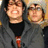 Two people in hooded jackets stand side-by-side; red pixelated text appears on black and gray backgrounds.