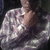 A person in a purple and white patterned shirt with a hand near their neck, shown in a four- with one blank