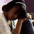 A person with dark hair and a white headband rests their head on another person's shoulder in a close embrace.